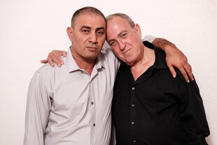Der Palästinenser Bassam Aramin schaut ernst, sein israelischer Freund Rami Elhanan liegt in seinem Arm und lehnt seinen Kopf an ihn .