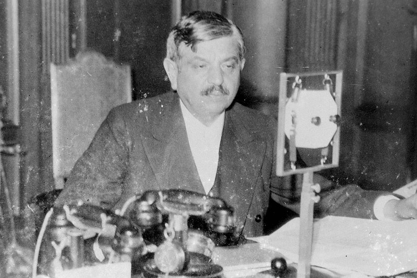 Pierre Naval sitzt vor einem Mikrofon