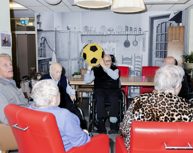 Mehrere Personen spielen in einer Pflegeeinrichtung mit einem Ball.