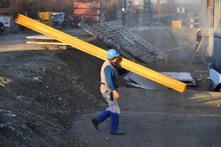 Ein Bauarbeiter trägt eine große Stange