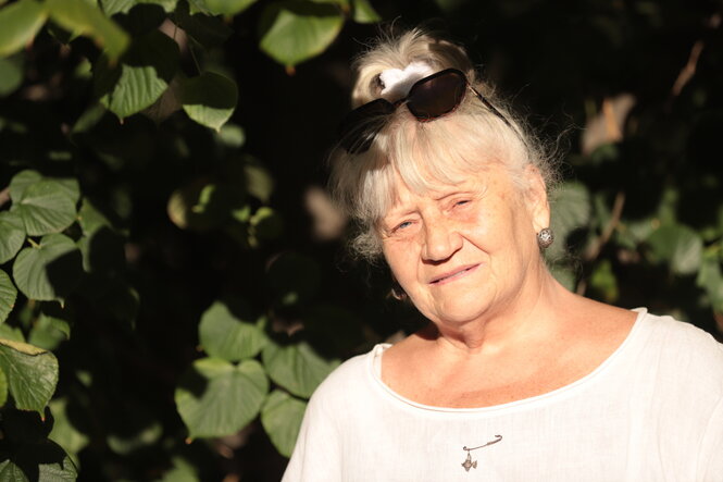 Eine Frau steht vor einem Baum in der Sonne
