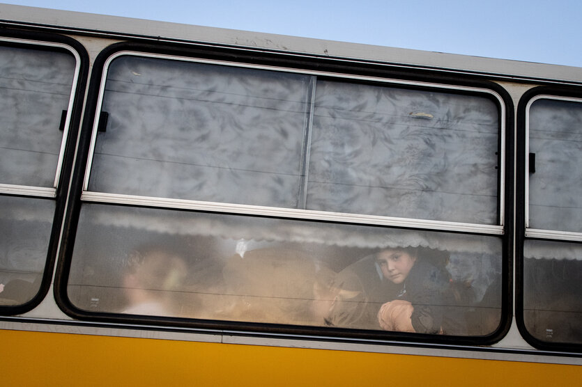 Ein Bus mit trüben Fenstern, dahinter Schemen von Menschen