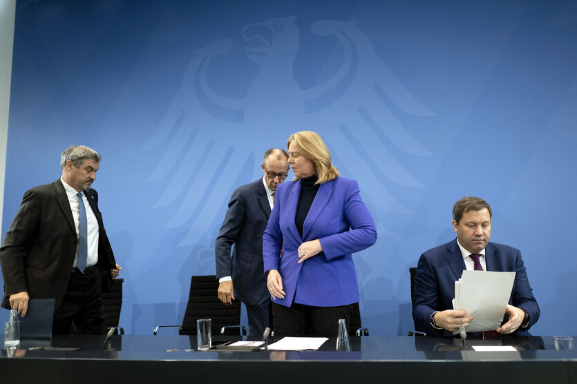 Drei Männer und eine Frau nach Verhandlungen vor einer blauen Wand