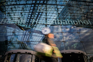 Ein Passant geht an der Uhr des Berliner Hauptbahnhofs vorbei. (Bewegungsunschärfe durch lange Belichtungszeit)