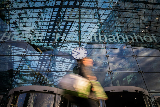 Ein Passant geht an der Uhr des Berliner Hauptbahnhofs vorbei. (Bewegungsunschärfe durch lange Belichtungszeit)