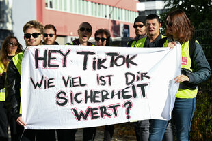 Menschen halten während einer Streikkundgebung von TikTok-Beschäftigten ein Plakat in der Hand, auf dem steht «Hey TikTok wie viel ist Dir Sicherheit wert?»
