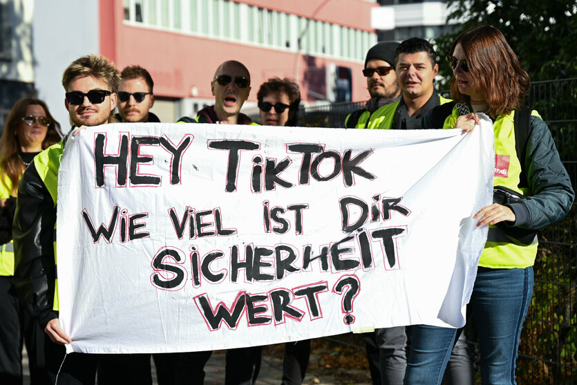 Menschen halten während einer Streikkundgebung von TikTok-Beschäftigten ein Plakat in der Hand, auf dem steht «Hey TikTok wie viel ist Dir Sicherheit wert?»