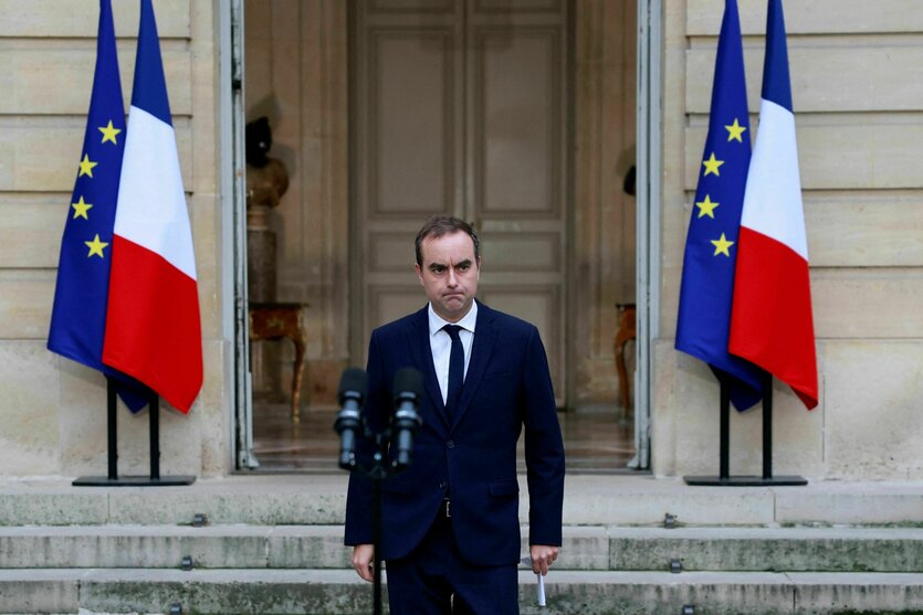 Sébastien Lecornu vor einem alten, pompösen Gebäude, davor stehen französische und EU-Flaggen