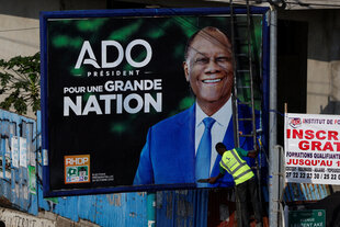 Ein Arbeiter stellt in Abidjan, Elfenbeinküste, am 10. Oktober 2025 ein Wahlplakat des ivorischen Präsidenten Alassane Ouattara, 83, auf, der bei der für den 25. Oktober angesetzten Präsidentschaftswahl eine vierte Amtszeit anstrebt.