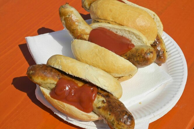Zwei Bratwürste im Brötchen auf einem Teller mit Ketchup.