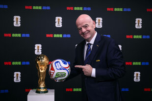 Fifa-Boss Gianni Infantino zeigt mit dem Finger auf einen Ball und die WM-Trophäe