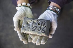 Ein Arbeiter hält einen Barren Seltener Erden in der Hand