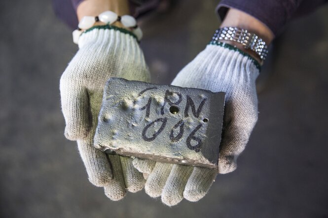 Ein Arbeiter hält einen Barren Seltener Erden in der Hand