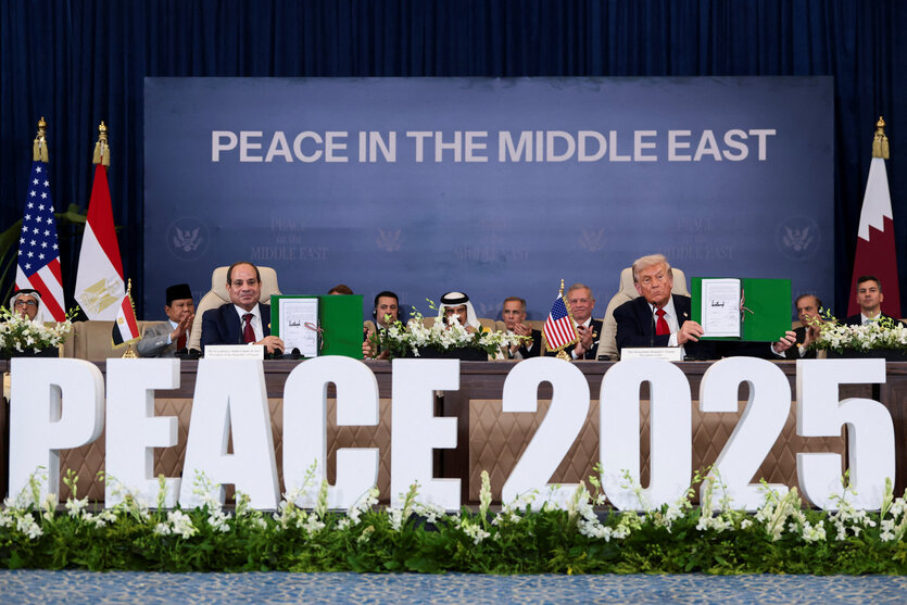 Menschen an einem Konferenztisch. Im Vordergrund der Schriftzug "PEACE 2025" in Großbuchstaben