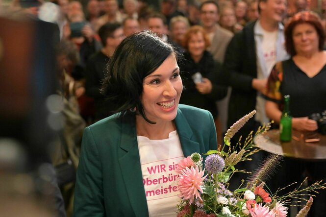 Potsdams neue Oberbürgermeisterin hält lächelnd einen Blumenstrauß nach ihrem Wahlsieg