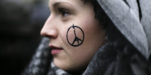 Eine Frau hat ein Friedenssymbol mit dem Eifelturm auf die Wange gezeichnet