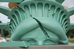 Der Kopf der Freiheitsstatue liegt zerschmettert auf dem Boden