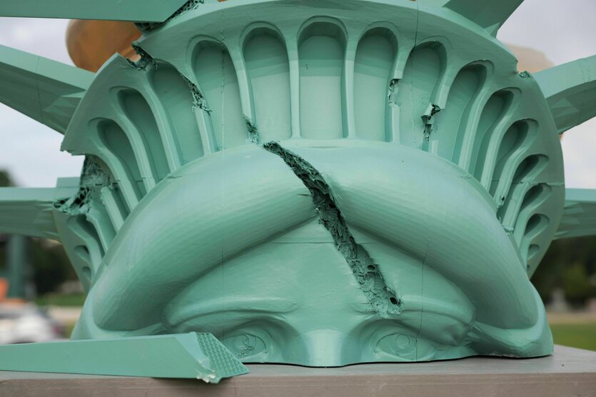 Der Kopf der Freiheitsstatue liegt zerschmettert auf dem Boden