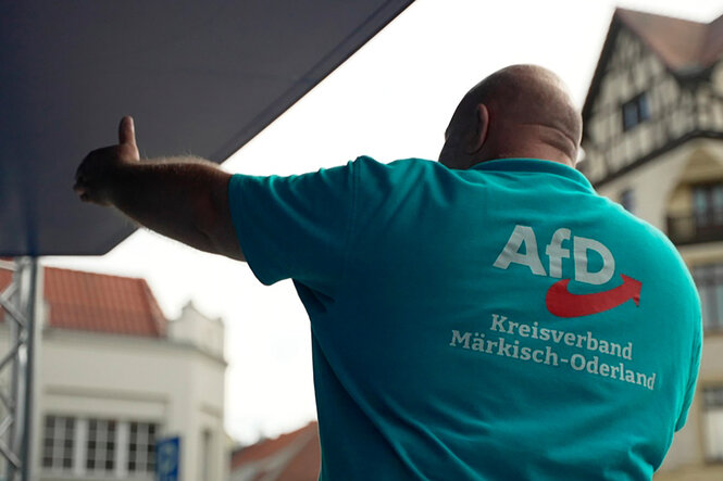 Ein Mann von hinten streckt seinen linken Arm aus