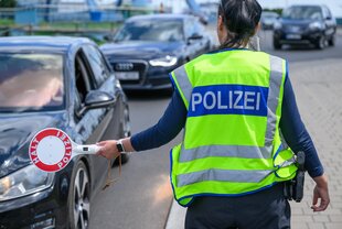 Polizistin hält eine rote Kelle am polnischen Grenzübergang heraus, um ein Auto zu stoppen