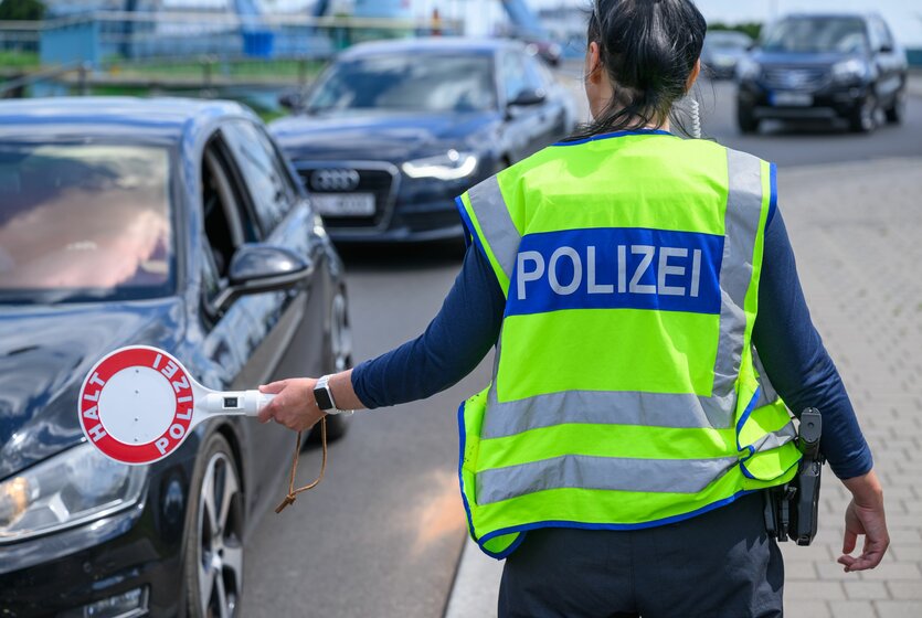 Polizistin hält eine rote Kelle am polnischen Grenzübergang heraus, um ein Auto zu stoppen
