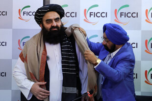 Ein indischer Abgeordnete hängt dem Außenminister des Taliban-Regimes am Monag bei einer Wirtschaftskonferenz in Delhi einen Begrüßungsschal um