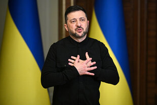Ein Mann steht vor zwei ukrainischen Flaggen