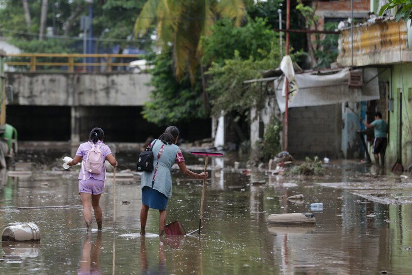 Menschen waten durch eine überflutete Straße in der Stadt Poza Rica