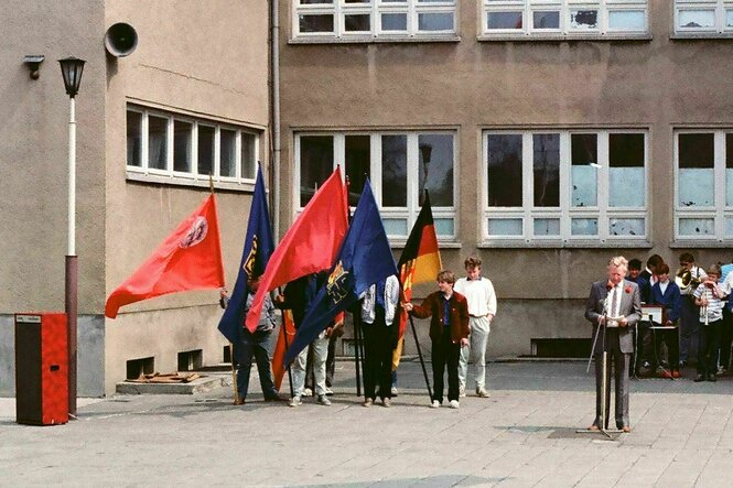 Jugendliche stehen mit Fahnen auf dem Schulhof