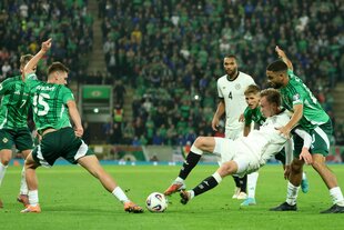 Die Füße eines deutschen und eines nordirischen Spielers gehen zum Ball, zwei Mitspieler beobachten die Szene