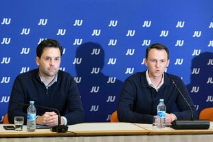 Johannes Winkel (links) und Pascal Reddig sitzen bei einer Pressekonferenz vor einer blauen Wand