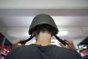 Ein Bundeswehrrekrut setzt seinen Helm auf
