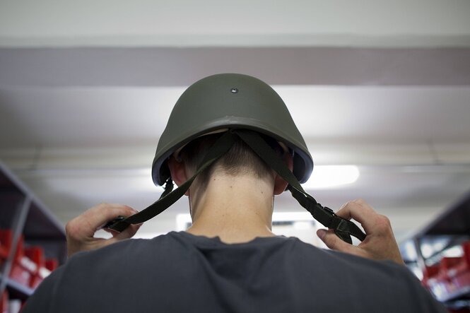 Ein Bundeswehrrekrut setzt seinen Helm auf
