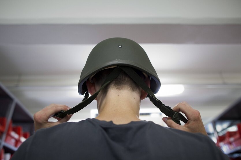 Ein Bundeswehrrekrut setzt seinen Helm auf