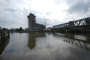 Der halbfertige Elbtower am Ende eines Hafenbeckens, rechts eine Eisenbahnbrücke