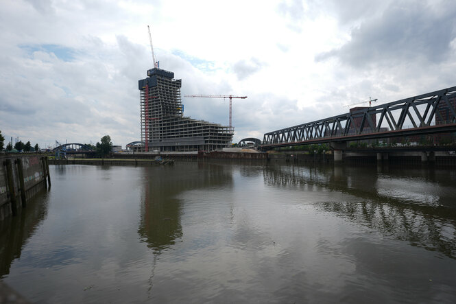 Der halbfertige Elbtower am Ende eines Hafenbeckens, rechts eine Eisenbahnbrücke