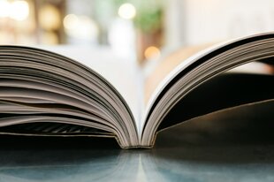 Ein aufgeschlagenes Buch liegt auf einem Tisch.