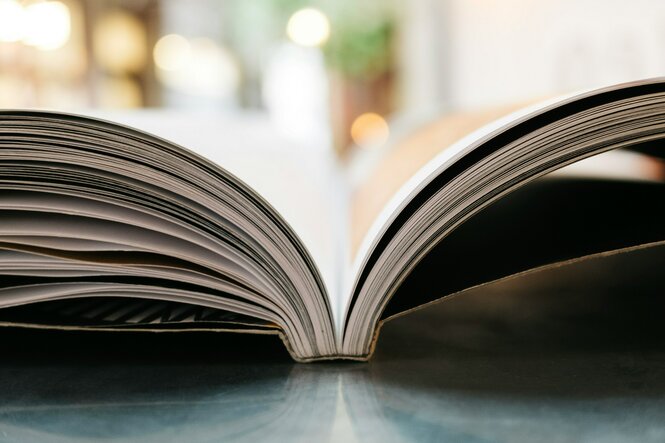 Ein aufgeschlagenes Buch liegt auf einem Tisch.