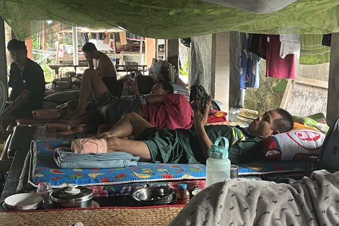 Personen auf Pritschen im provisorischen Krankenhaus, im Vordergrund ein Widerstandskämpfer aus Myanmar mit einem amputierten Bein