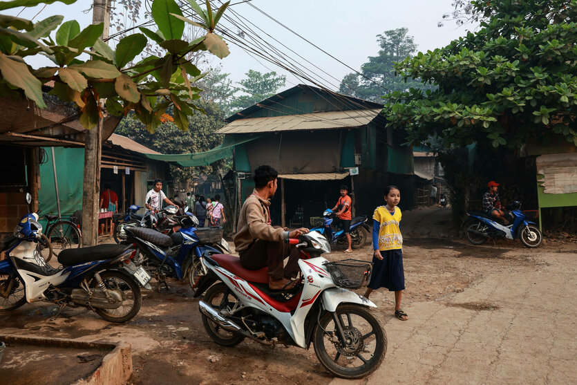Mehrere Personen auf einer Straße zu Fuß und mit Moped im Lager Mae La in Mae Sot für Flüchtlinge vom Volk der Karen aus Myanmar, das bereits seit 50 Jahren besteht.