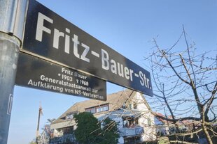 Im Vordergrund ein Straßenschild in Stuttgart-Sillenbuch, das den Namen von Fritz Bauer trägt, im Hintergrund sind die Häuser der Siedlungsstraße.