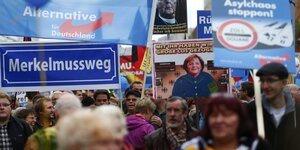Demonstranten der AfD, die Schilder tragen, auf denen "Merkel muss weg" und anderes steht