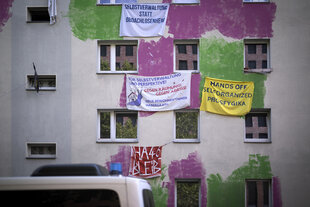 Farbflächen in Grün und Lila und Transparente hängen an der Hausfassade der Habersaathstrasse 40-48