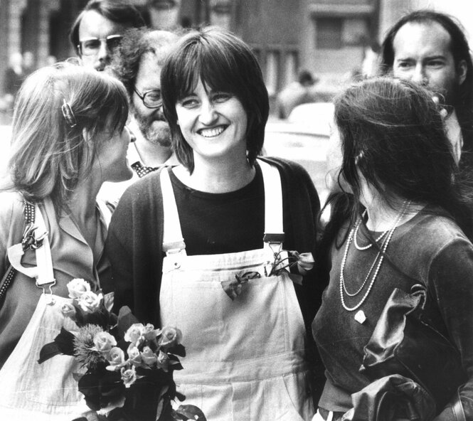 Astrid Proll in Latzhose lächelt, als sie mit Blumen von Freunden empfangen wird
