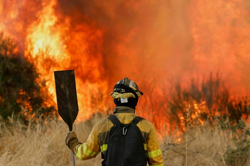 Ein Feuerwehrmann steht vor einem riesigen Feuer
