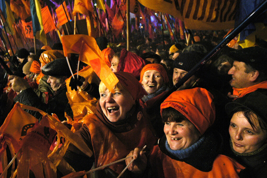Fröhliche Protestierende schwenken orangene Fahnen