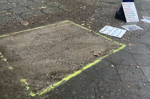 Ein helles Rechteck auf einem Gehweg und Protestplakate