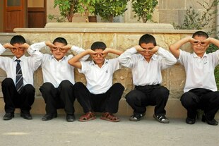 Schühler hocken in einer Reihe und machen Faxen