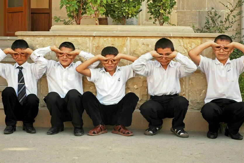 Schühler hocken in einer Reihe und machen Faxen