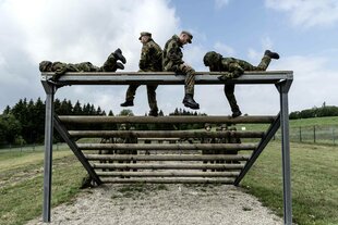 Mehrere Soldaten sitzen und liegen auf einem Geländer